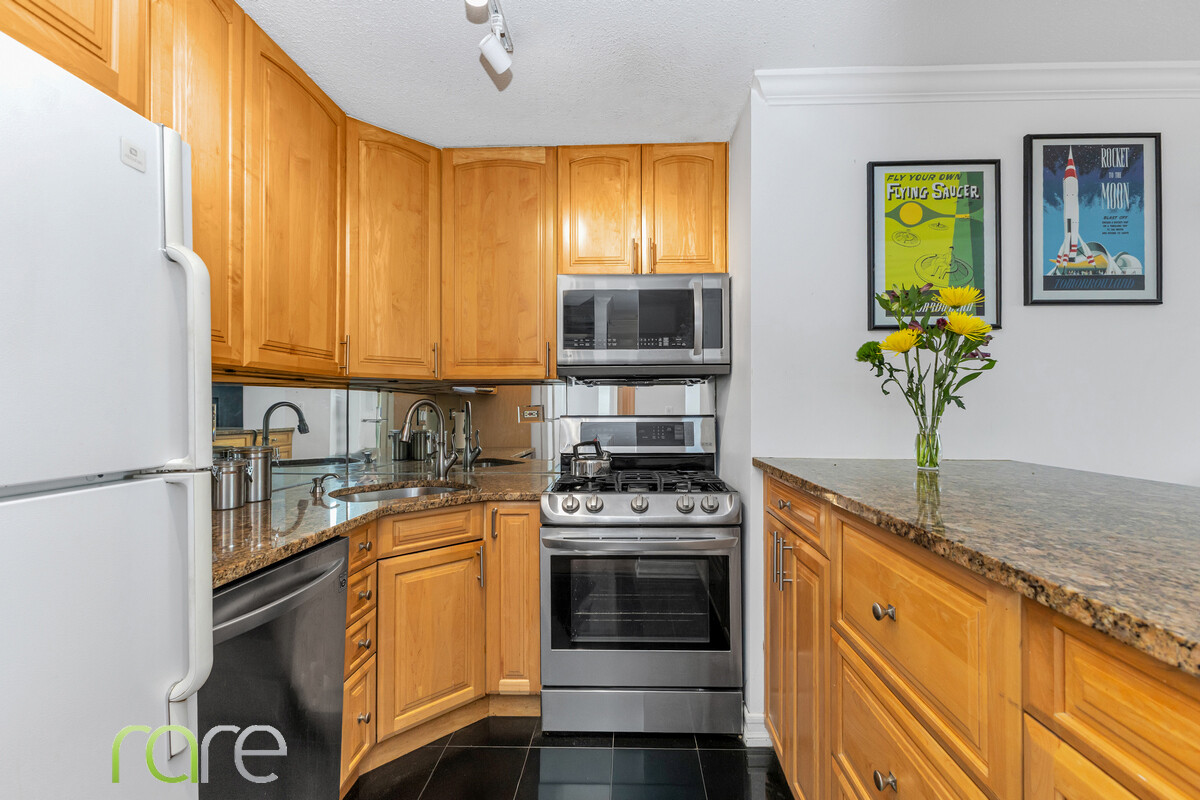 340 East 93rd Street, Unit 23G Manhattan, NY 10128 - Photo 3 of 16 a kitchen with a stove a sink and a microwave