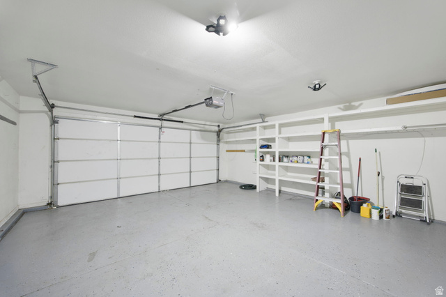 1440 West 100 South Virgin, UT 84779 - Photo 31 of 45 Spacious garage featuring two overhead doors, built-in shelving, and a speckled epoxy floor finish