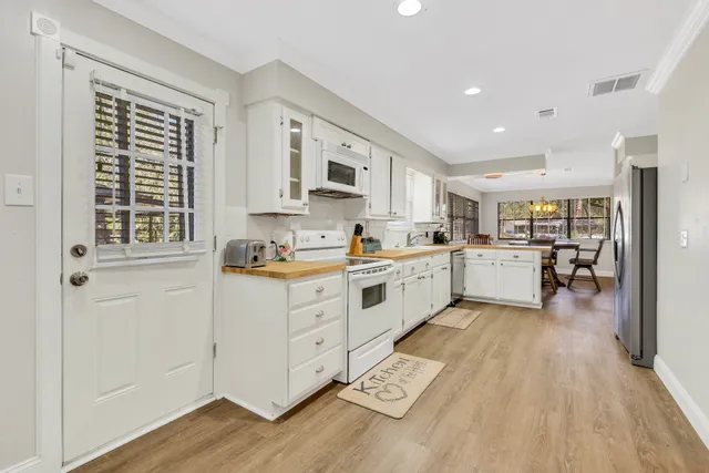 a kitchen with white cabinets and wooden floor