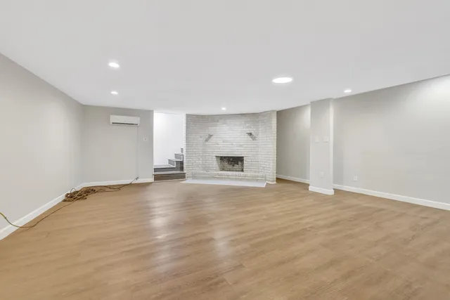 an empty room with wooden floor and fireplace