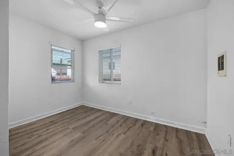 an empty room with wooden floor fan and windows