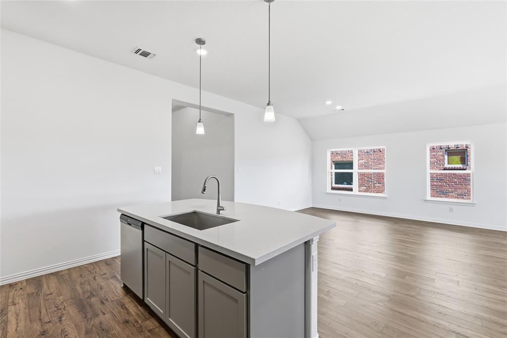 2529 Rivers W Road Anna, TX 75409 - Photo 15 of 40 Kitchen island featuring a stainless steel sink, gooseneck faucet, and integrated dishwasher