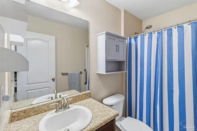 a bathroom with a granite countertop toilet sink and mirror