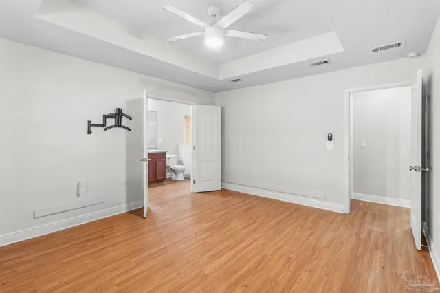 an empty room with wooden floor and a ceiling fan