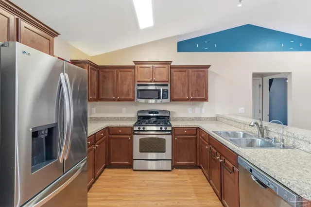 a kitchen with stainless steel appliances granite countertop a refrigerator stove and sink