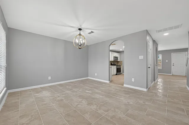 a view of an empty room and chandelier fan