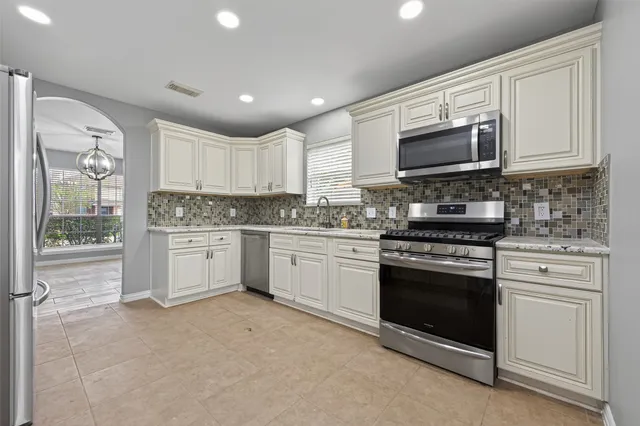 a kitchen with white cabinets stainless steel appliances and a sink