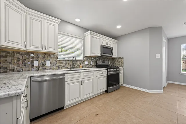 a kitchen with stainless steel appliances granite countertop a stove a sink and a microwave