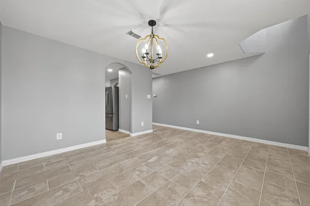 a view of an empty room and chandelier fan