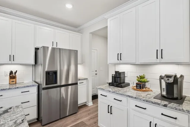 a kitchen with stainless steel appliances a sink dishwasher a stove a refrigerator and a dining table with wooden floor