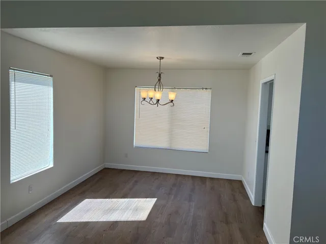 an empty room with wooden floor windows and cabinet
