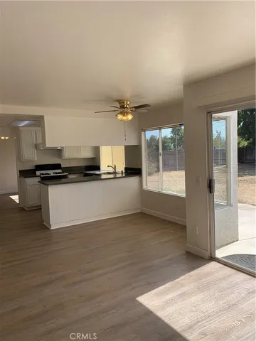 a view of a kitchen with a sink and dishwasher a stove top oven with wooden floor
