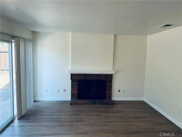 an empty room with wooden floor and fireplace