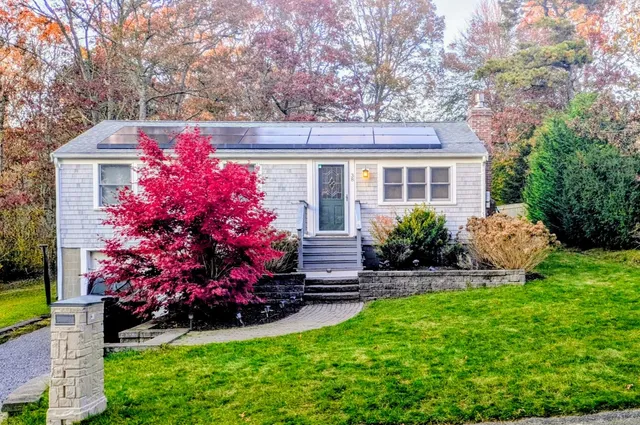 a front view of a house with a yard and potted plants