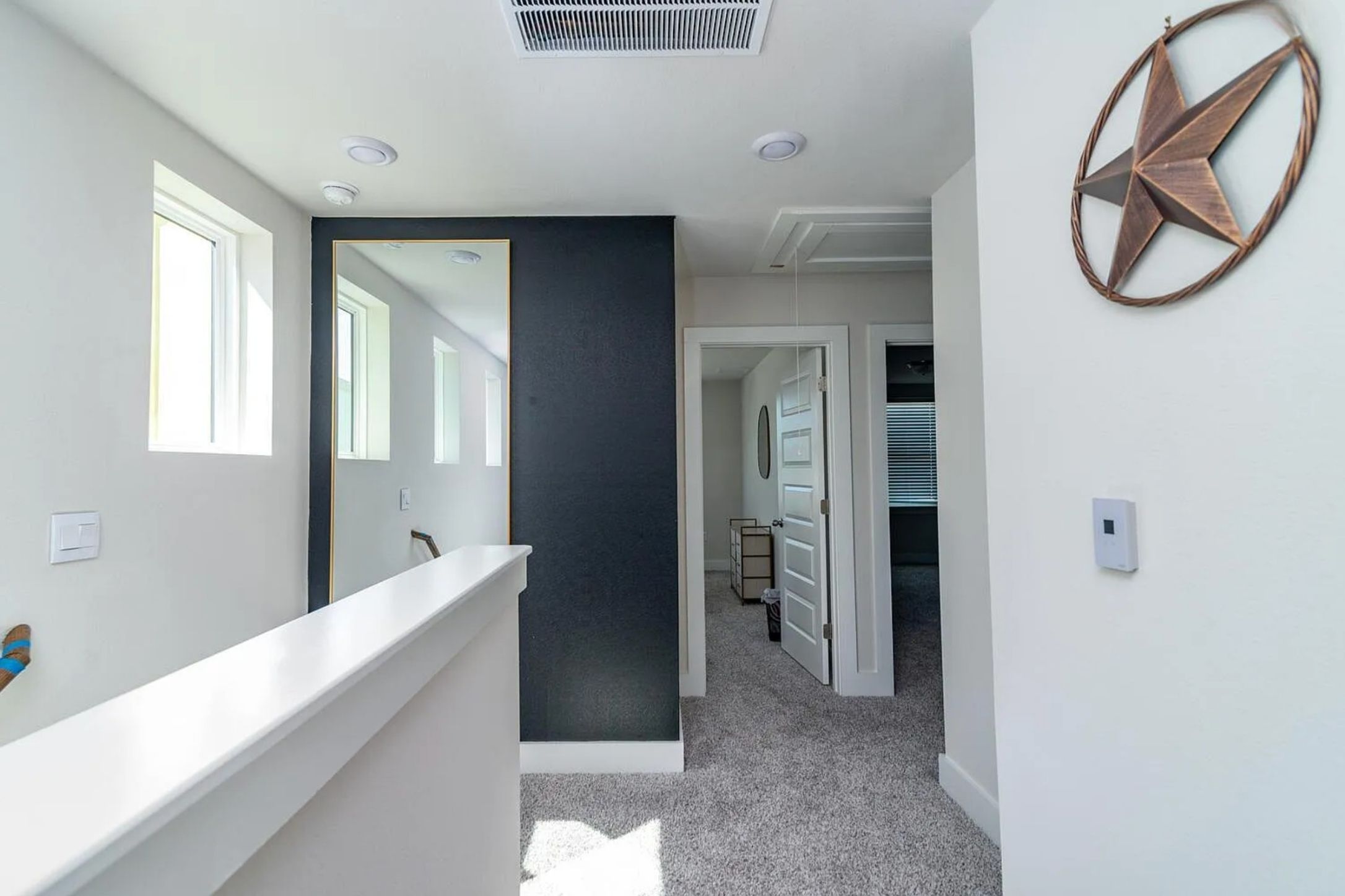 7501 Travertine Spring Drive Austin, TX 78744 - Photo 12 of 28 Carpeted hallway featuring white walls, recessed lighting, and a dark accent wall with a full-length mirror