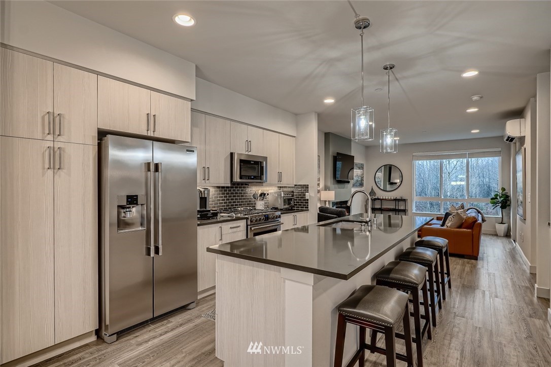 17905 35th Avenue Southeast, Unit A3 Bothell, WA 98012 - Photo 10 of 35 a kitchen with stainless steel appliances granite countertop a refrigerator a stove a sink a dining table and chairs with wooden floor