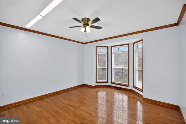 a view of empty room with wooden floor and fan