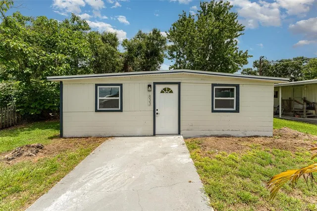 a backyard of a house with plants and large tree