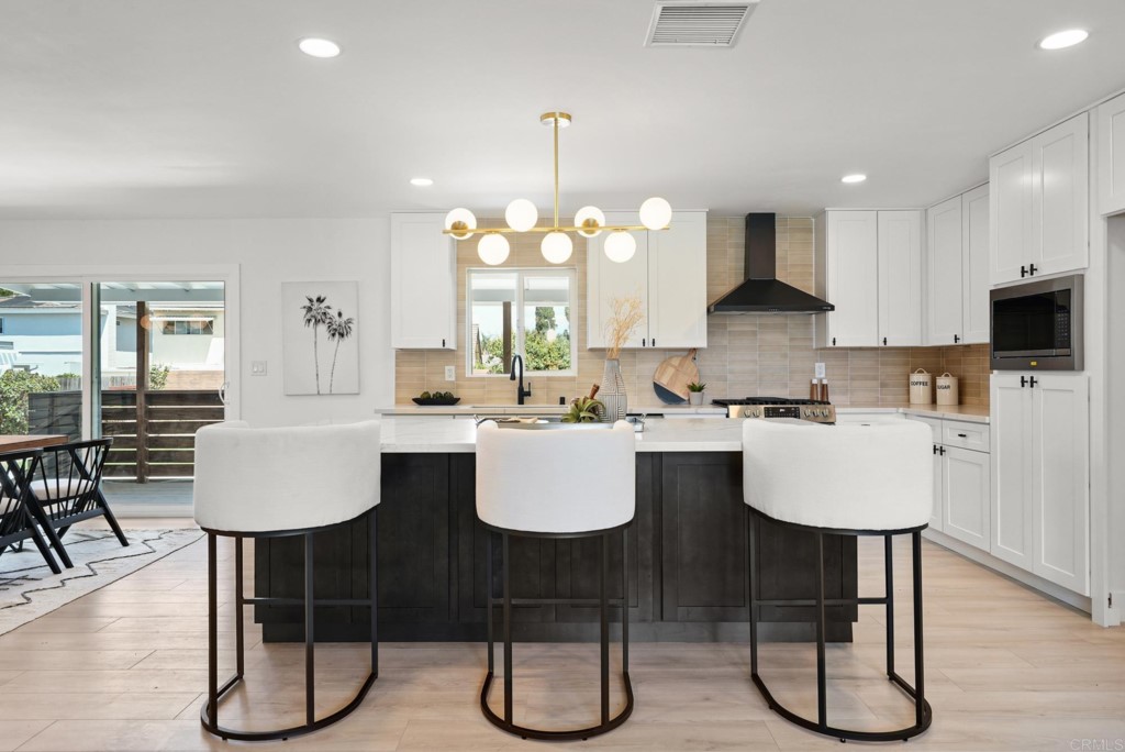 6125 Laport Street La Mesa, CA 91942 - Photo 11 of 32 a kitchen with kitchen island granite countertop a table chairs a sink a window and cabinets