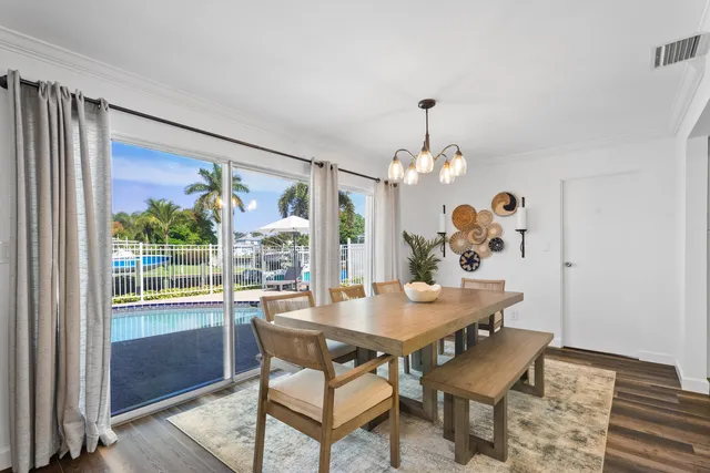 a dining room with wooden floor a chandelier a wooden table and chairs