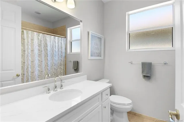 a bathroom with a granite countertop toilet a sink and mirror