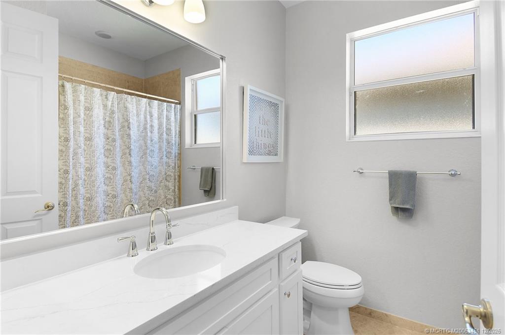 3141 Southwest Porpoise Circle Stuart, FL 34997 - Photo 16 of 45 a bathroom with a granite countertop toilet a sink and mirror