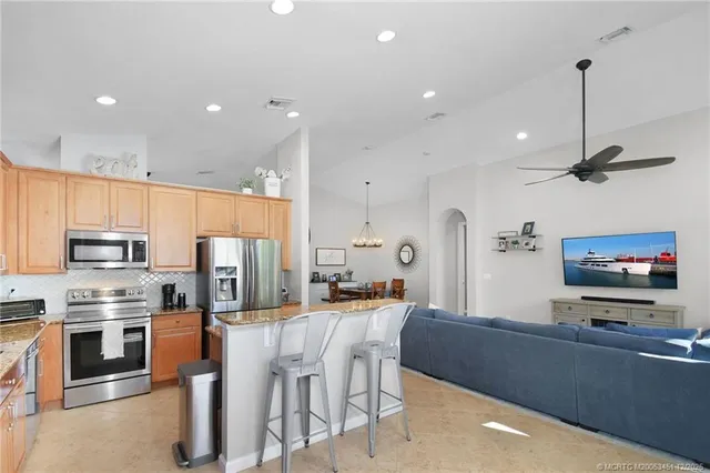 a kitchen with stainless steel appliances kitchen island granite countertop a refrigerator and a stove top oven