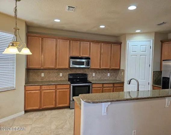 a kitchen with granite countertop white cabinets and stainless steel appliances