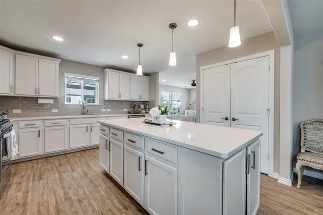 a kitchen with kitchen island granite countertop a sink a counter space appliances and cabinets