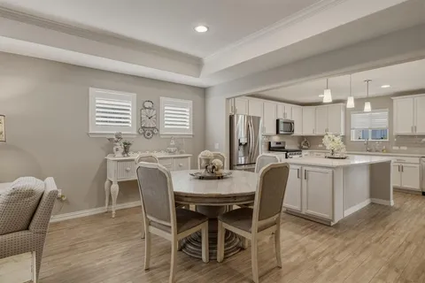 a kitchen with a dining table chairs and wooden floor