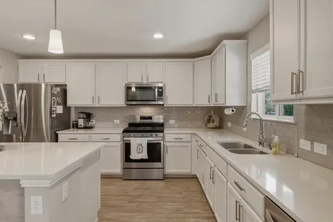 a kitchen with kitchen island granite countertop a sink a counter space stainless steel appliances and cabinets