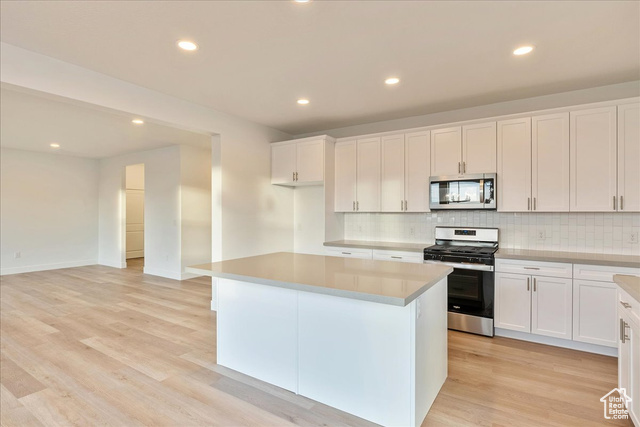 2033 Fortune Lane, Unit 462 Mapleton, UT 84664 - Photo 10 of 27 Kitchen with light hardwood / wood-style flooring, a kitchen island with gray quartz counter tops, white cabinets, and appliances with stainless steel finishes
