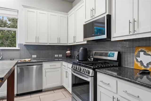a kitchen with granite countertop white cabinets stainless steel appliances and a sink