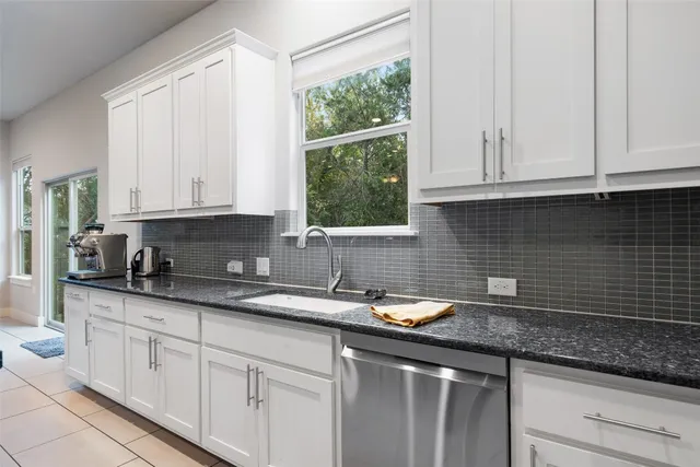 a kitchen with granite countertop white cabinets white appliances and a sink