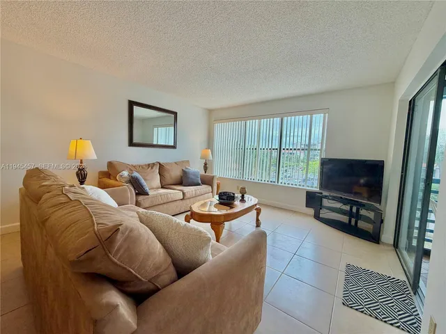 a living room with furniture a flat screen tv and a window