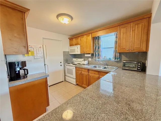 a large kitchen with stainless steel appliances a sink a stove and a refrigerator