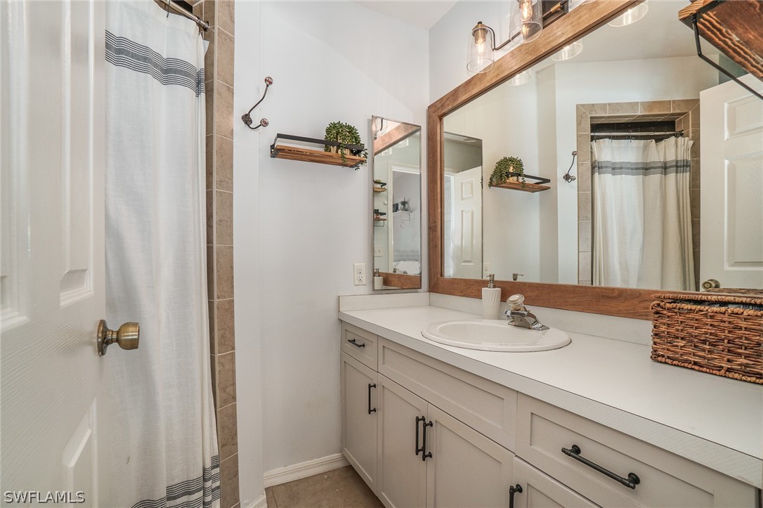 18210 Oak Road Fort Myers, FL 33967 - Photo 10 of 23 a bathroom with a granite countertop sink a mirror and shower