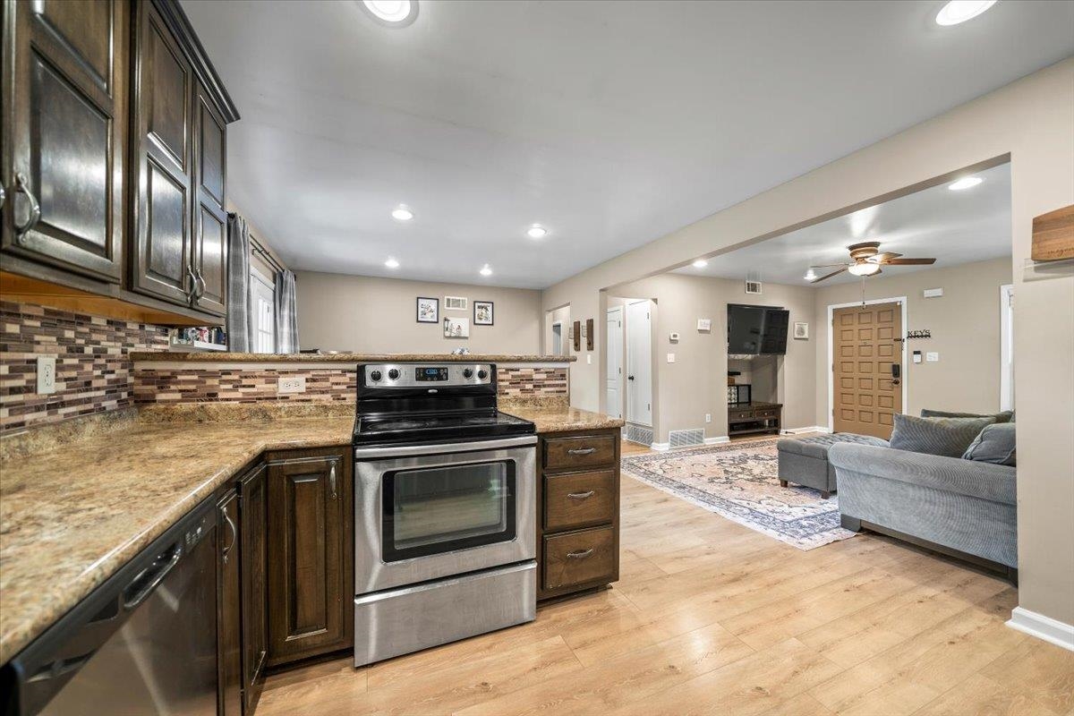 4686 Bill Knight Road Millington, TN 38053 - Photo 15 of 29 Kitchen with dark wood cabinetry, granite-finish countertops, stainless steel appliances, and a mosaic tile backsplash