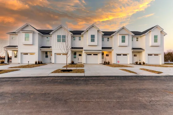 a view of a white house with a large space and a car parked on the road