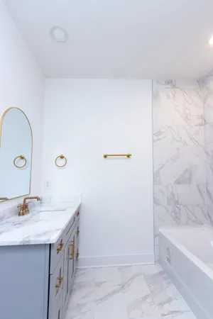 a bathroom with a granite countertop sink a mirror and a bathtub