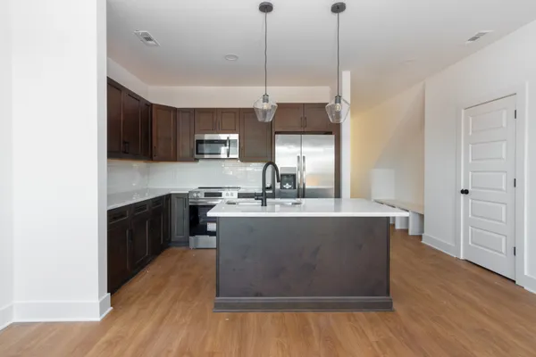 a kitchen with kitchen island a sink a stove a microwave and wooden floors