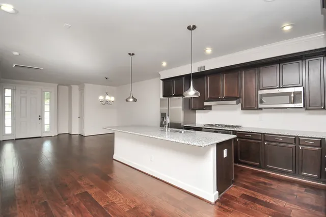 a large kitchen with stainless steel appliances granite countertop a sink a stove and a wooden floors