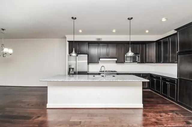 a kitchen with kitchen island granite countertop a sink stainless steel appliances and cabinets