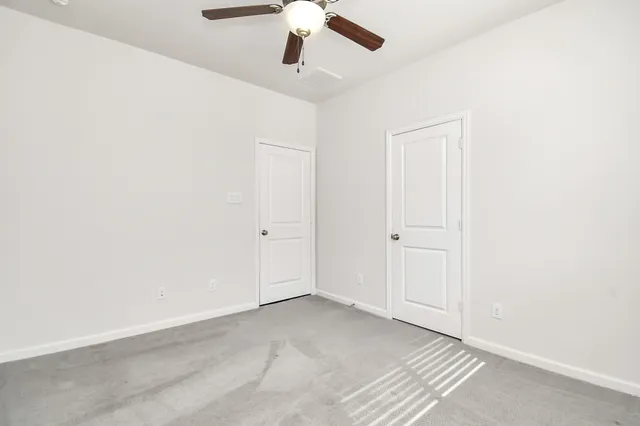 an empty room with a ceiling fan and carpet