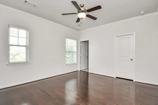 a view of an empty room with a window and wooden floor