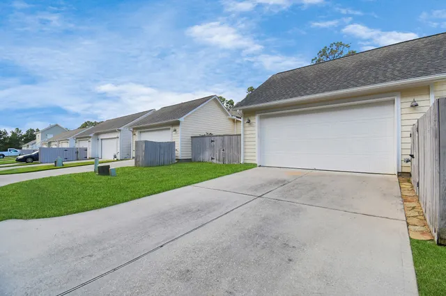 a view of a white house next to a yard and large trees