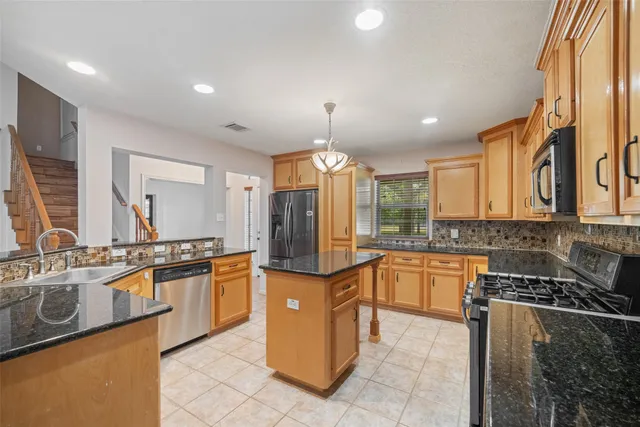 a kitchen with stainless steel appliances granite countertop sink stove and refrigerator