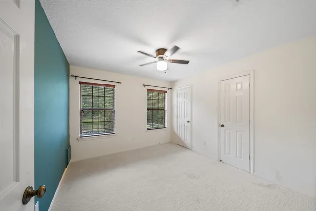 an empty room with chandelier fan and windows