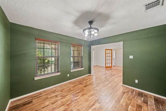 a view of an empty room with a window and wooden floor
