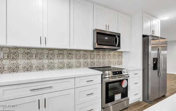 a kitchen with stainless steel appliances granite countertop white cabinets and a stove a oven with wooden floor
